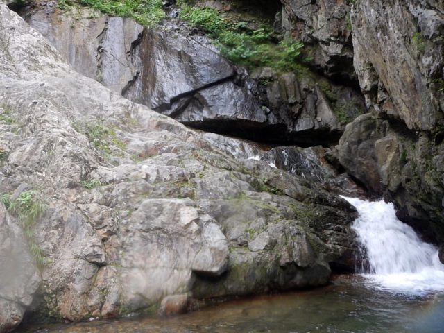岩場の裏側を落ちるトイ状の滝